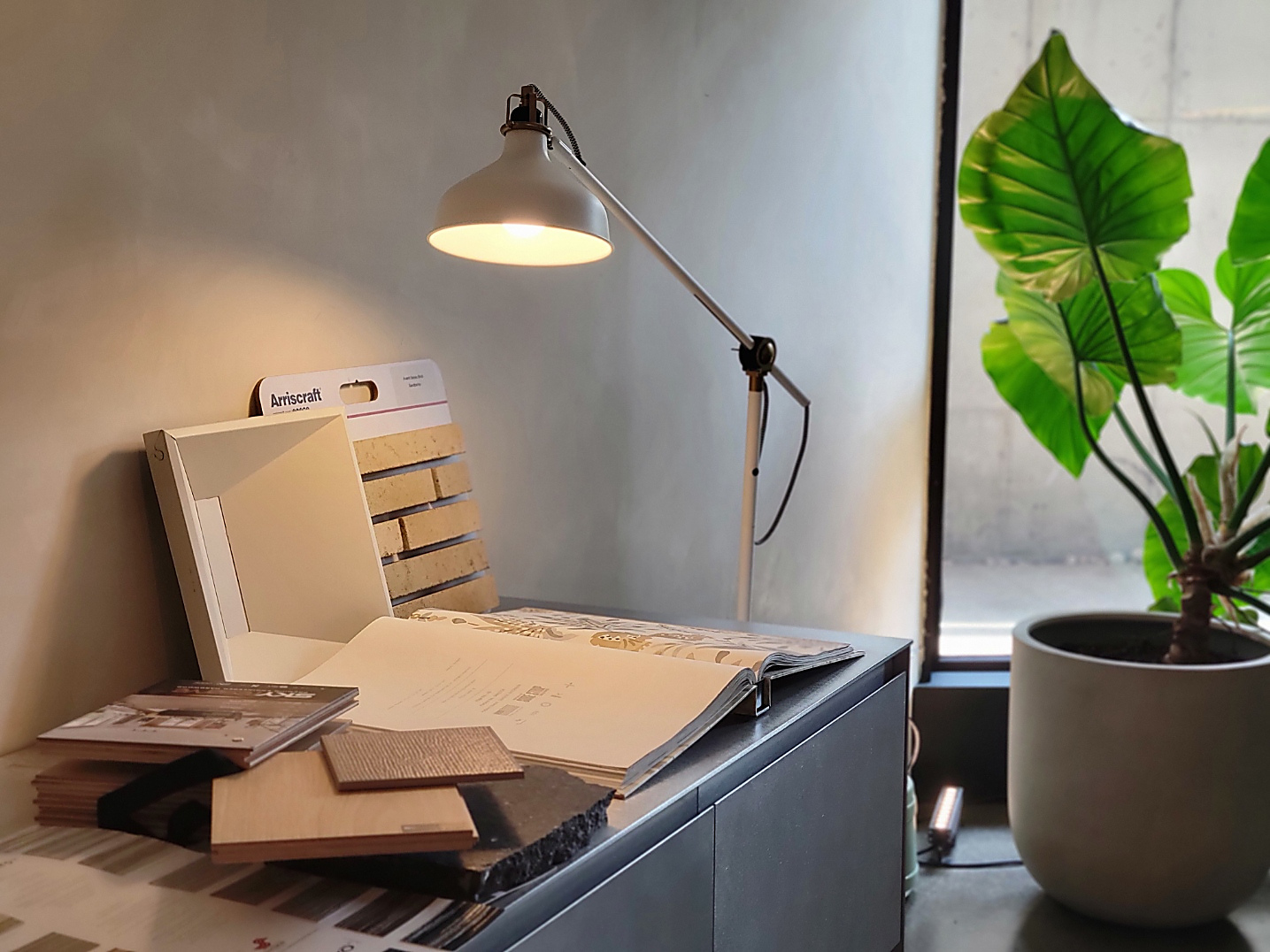 Material samples and a task lamp on a console in the HI Design Studio office